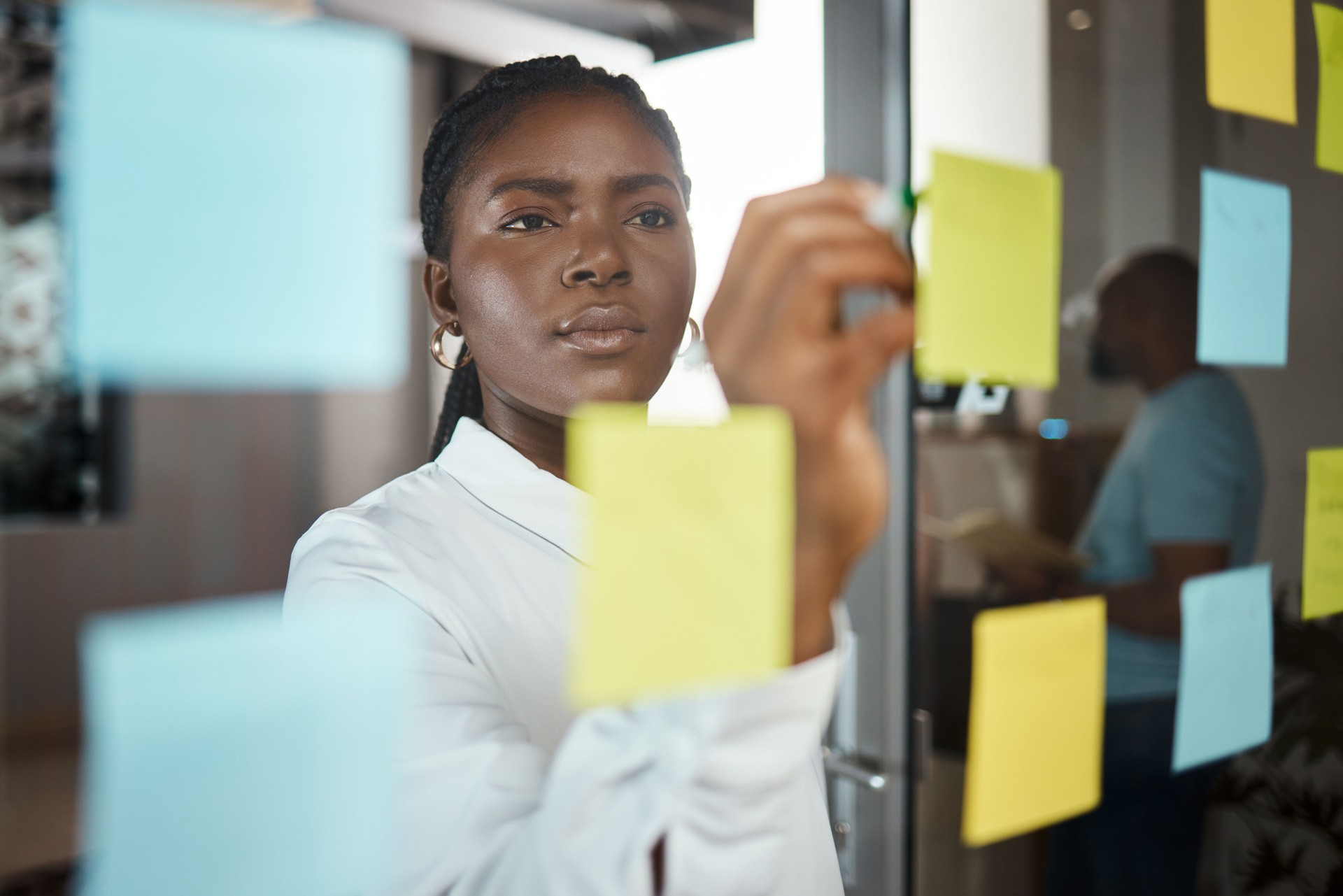 Shot of a businesswoman brainstorming with sticky notes on a glass screen