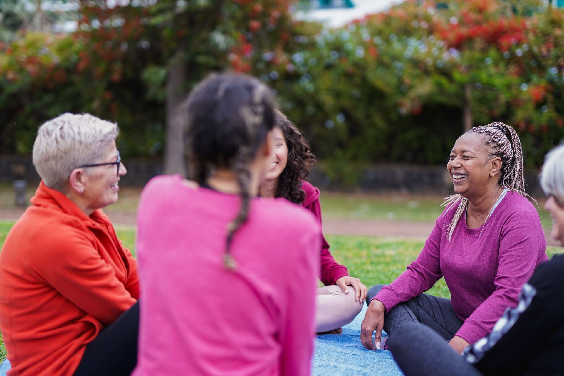 Group of happy multi generational women having fun sitting in a circle at city park - Community, multiracial people and social gathering concept