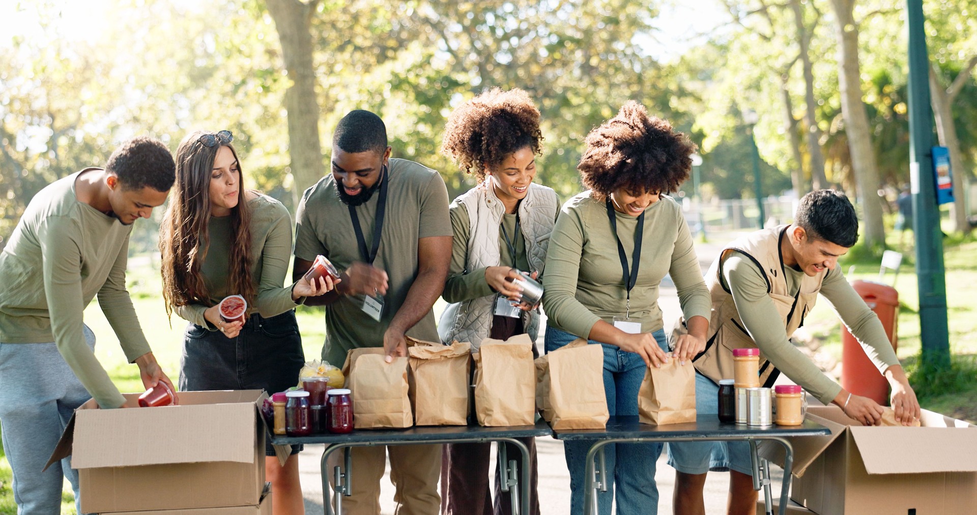 People, volunteering and help package or outdoor, kindness ngo and charity project with community in park. Distribution, food parcel and grocery boxes for donation, teamwork and collaboration