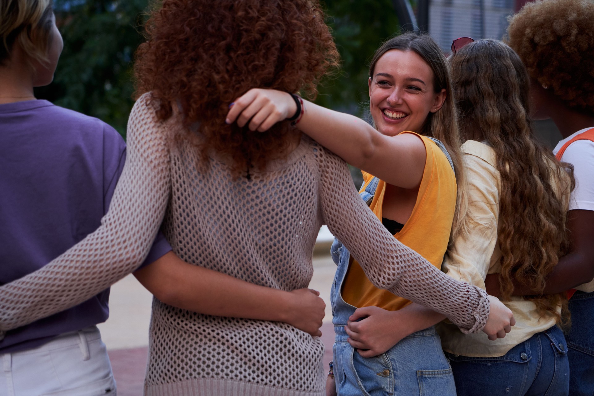 Group of happy young multiracial people embracing together outdoors.