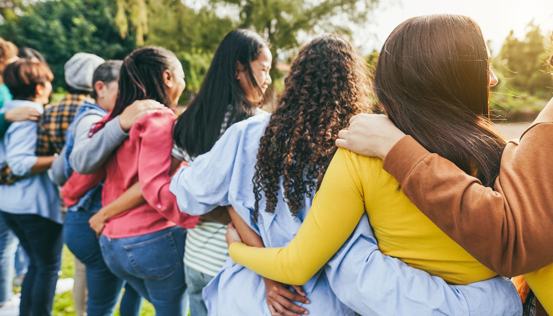 Multi generational women hugging each others - Female multiracial group having fun togheter outdoor - Firendship and people support concept - Main focus on right girl head